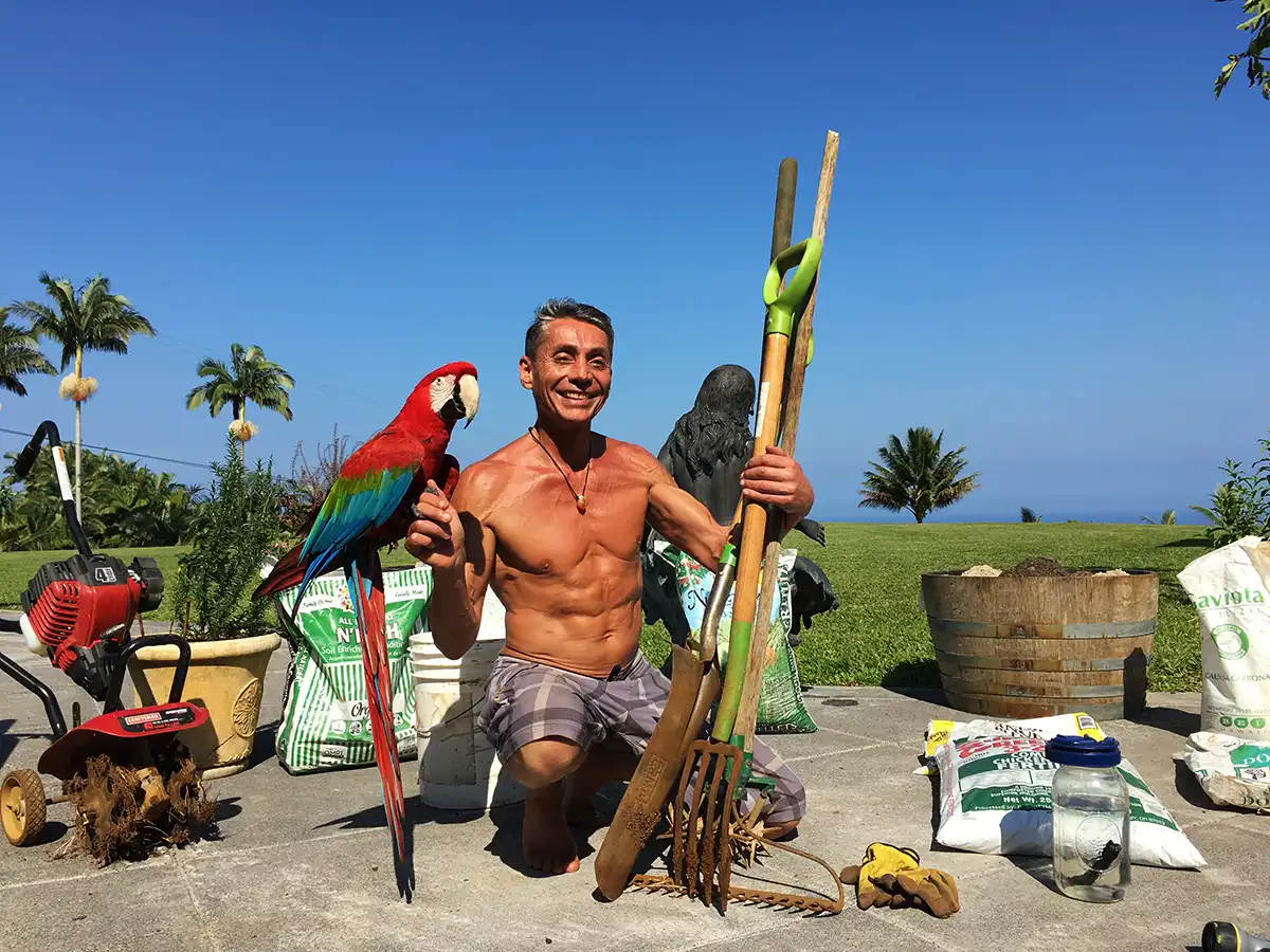 Dr. Robert Cassar posing with his gardening tools with blue sky